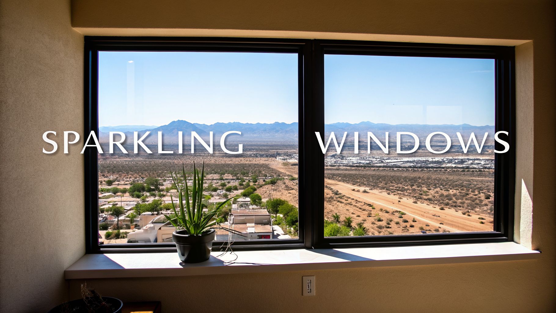 A large window overlooks a desert landscape with mountains, a town, and a plant, showcasing sparkling clean glass.